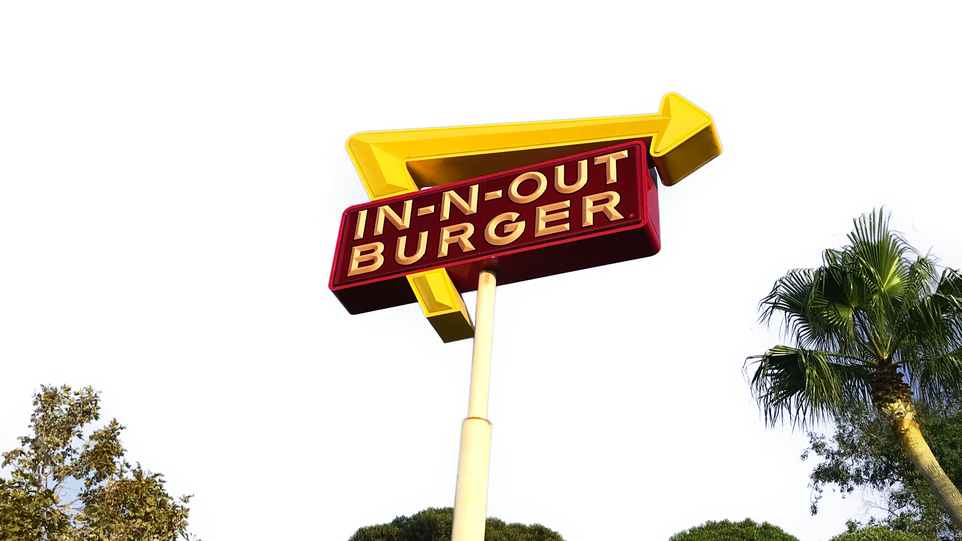 Cartel luminoso de In-N-Out Burger con una palmera al atardecer